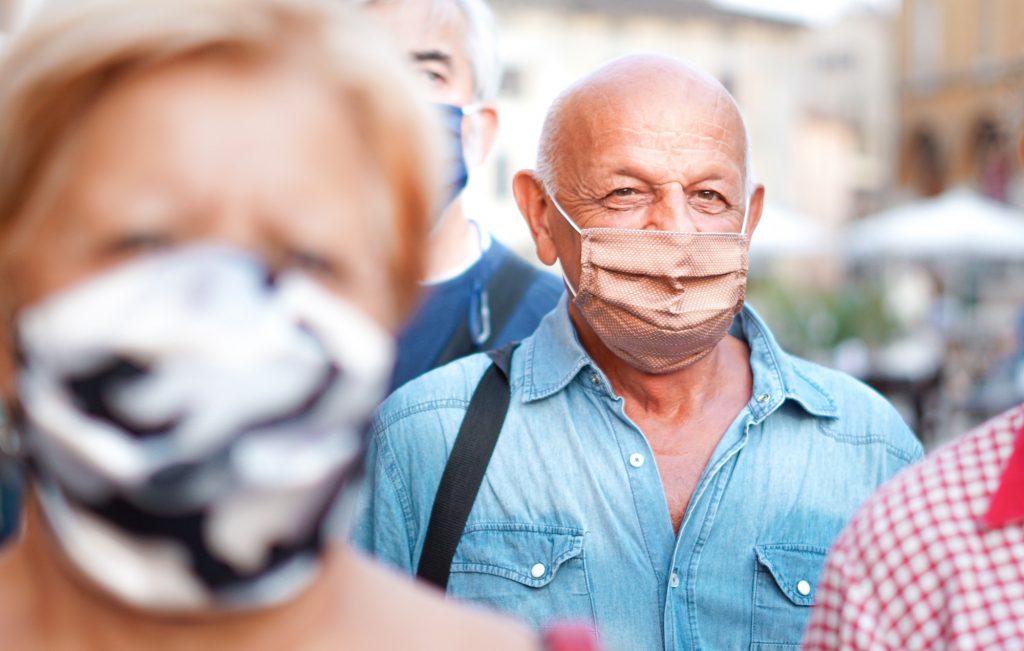 Crowd of people walking down the city streets with face mask on